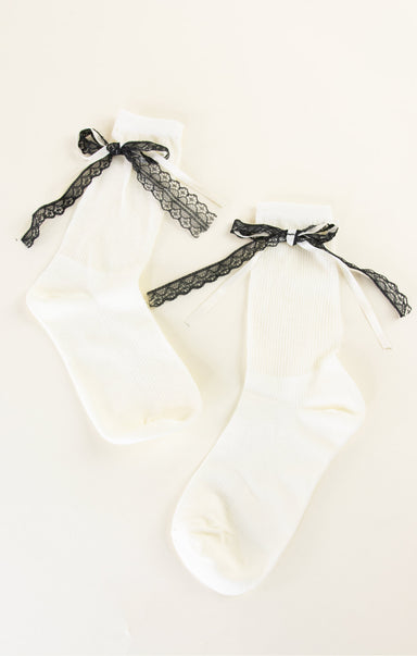 White baby outfit with black lace details on a white background