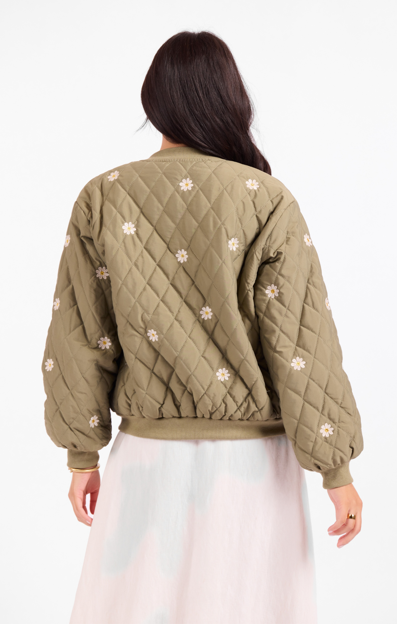 Person wearing a green quilted jacket with floral patterns on a white background