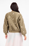 Person wearing a green quilted jacket with floral patterns on a white background