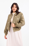 Woman wearing a green quilted jacket with floral patterns on a white background