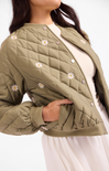 Green quilted jacket with floral embroidery on a white background