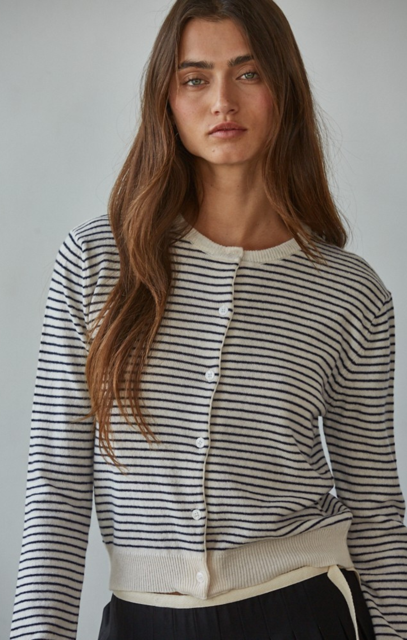 Woman wearing a black and white striped cardigan against a plain background