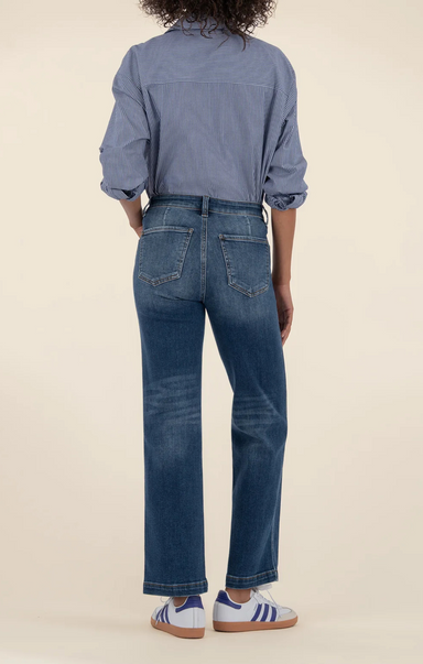 Person wearing a blue shirt and jeans on a beige background