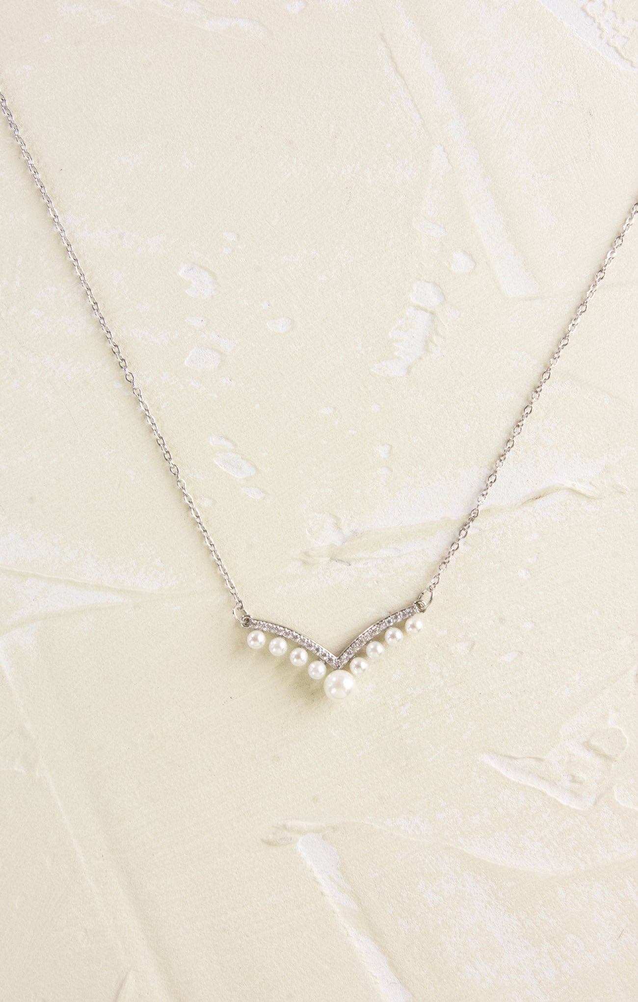 Pearl necklace on a textured beige background