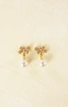 Gold earrings with pearl drops on a beige background