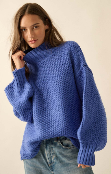 Woman wearing a blue knitted sweater against a plain background