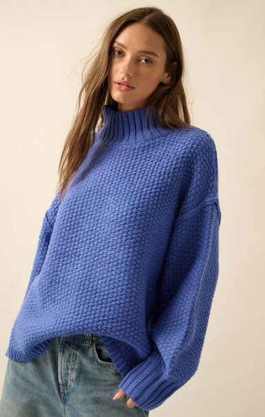 Woman wearing a blue knitted sweater against a plain background