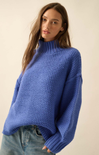 Woman wearing a blue knitted sweater against a plain background