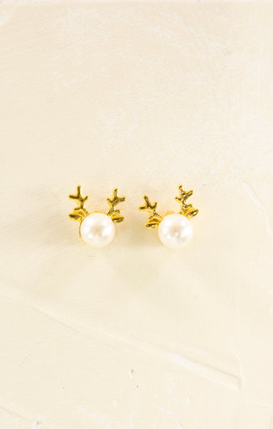 Pair of gold antler earrings with pearl centers on a beige background