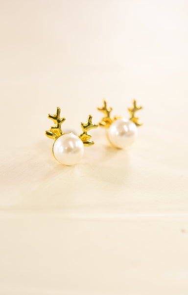 Pair of pearl earrings with gold antler-like designs on a beige background