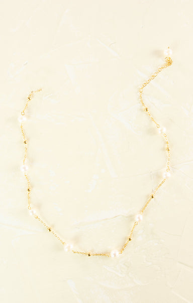 Gold necklace with pearls on a beige background