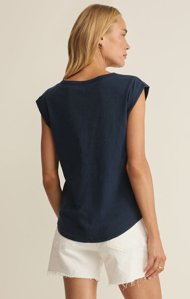 Woman wearing a navy blue sleeveless top and white shorts on a beige background