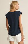 Woman wearing a navy blue sleeveless top and white shorts on a beige background
