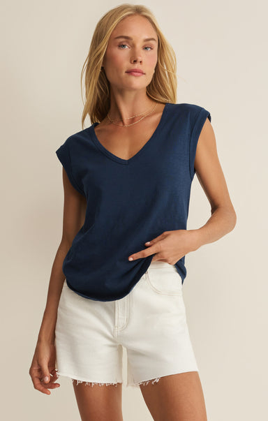 Woman wearing a navy blue sleeveless top and white shorts on a beige background