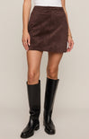 Person wearing a brown suede skirt and black knee-high boots on a beige background