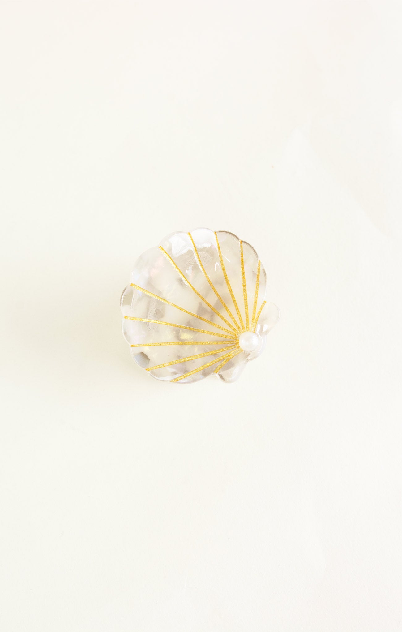 Shell-shaped object with gold accents on a white background
