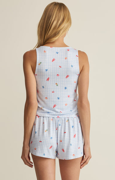 Woman wearing a light blue sleeveless top and shorts with colorful patterns on a beige background