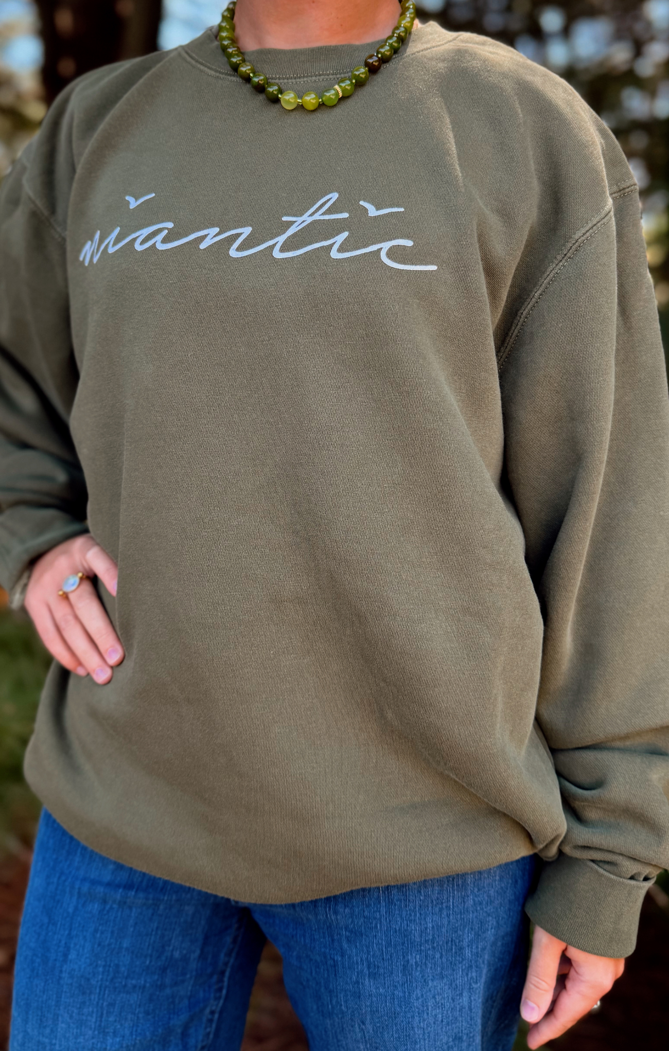 Person wearing an olive green sweatshirt with 'Wantic' printed on it, standing outdoors.
