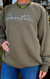 Person wearing an olive green sweatshirt with 'Wantic' printed on it, standing outdoors.