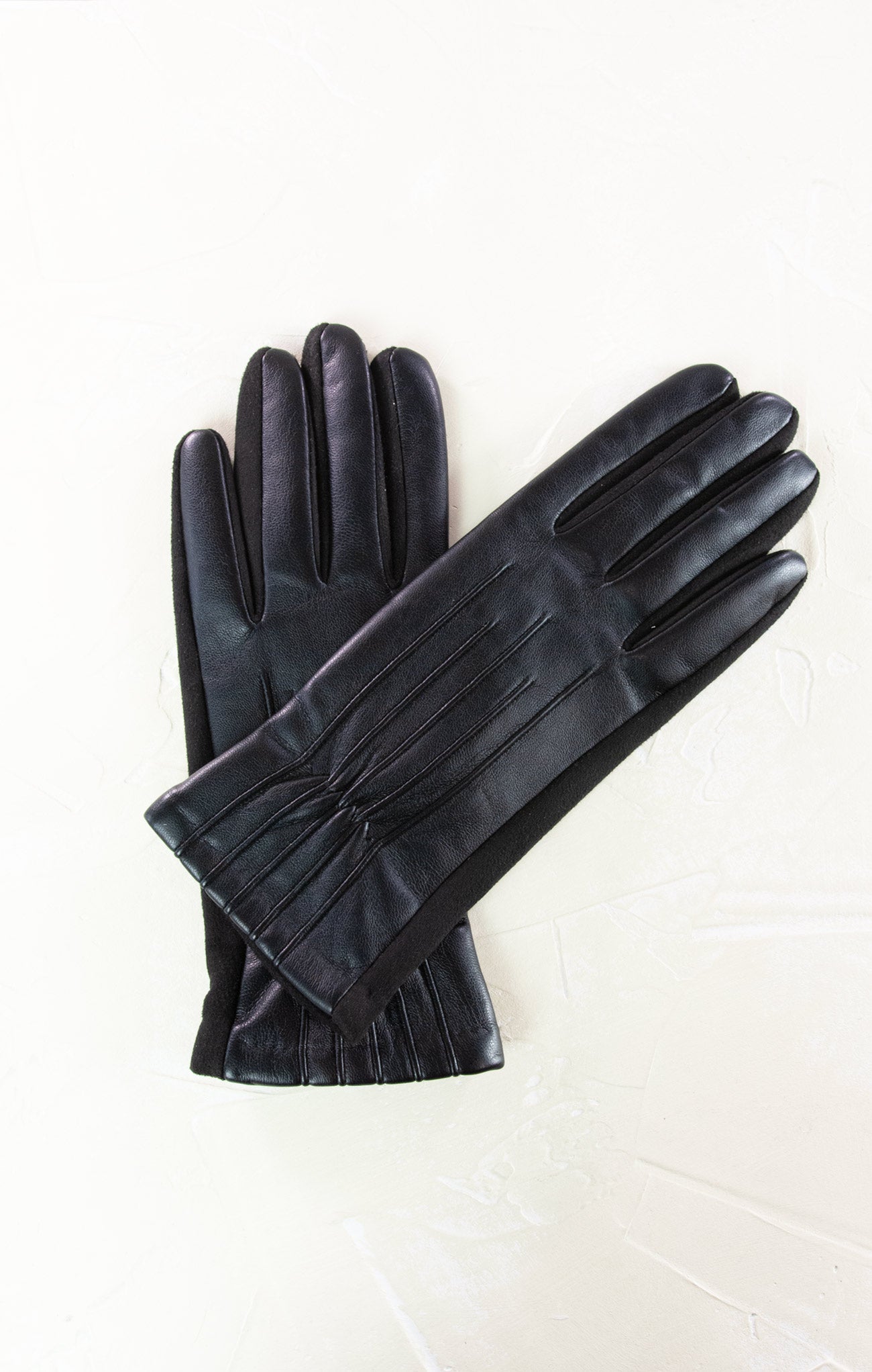 Pair of black leather gloves with a bow on a white background
