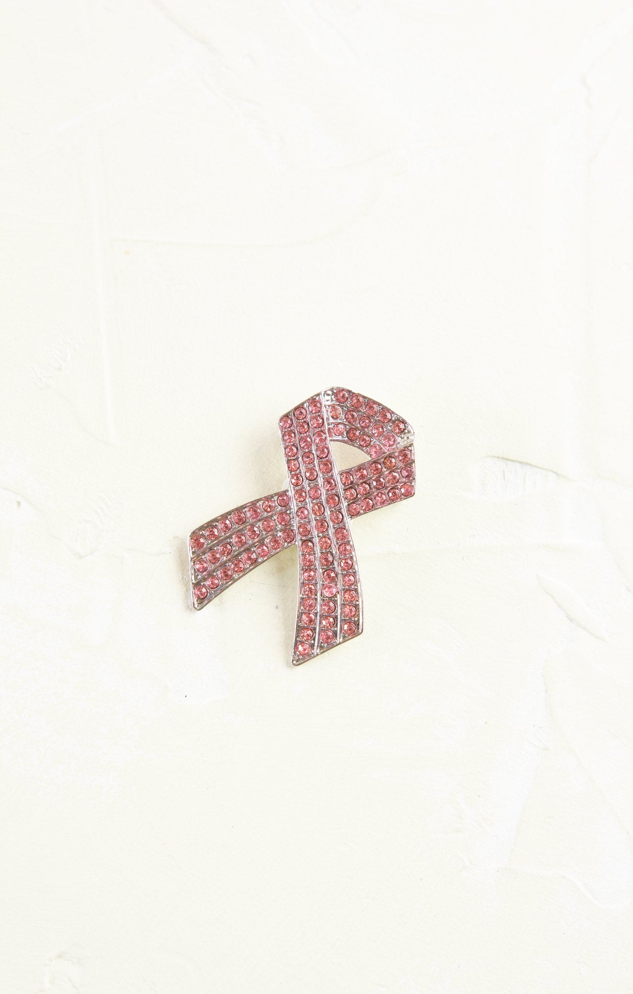 Pink ribbon brooch with crystals on a white background