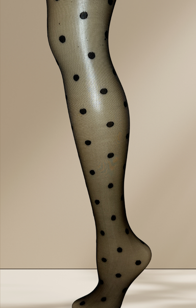 Leg wearing polka dot tights against a beige background