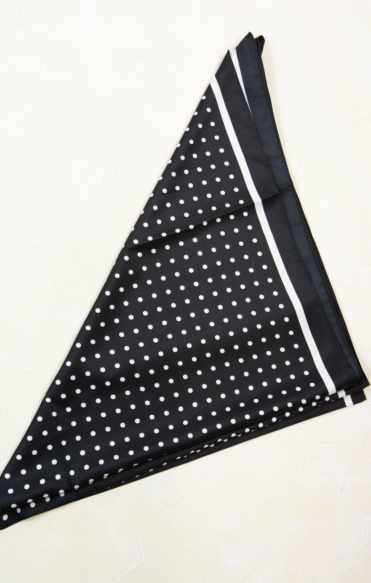 Black fabric with white polka dots and a white border on a white background