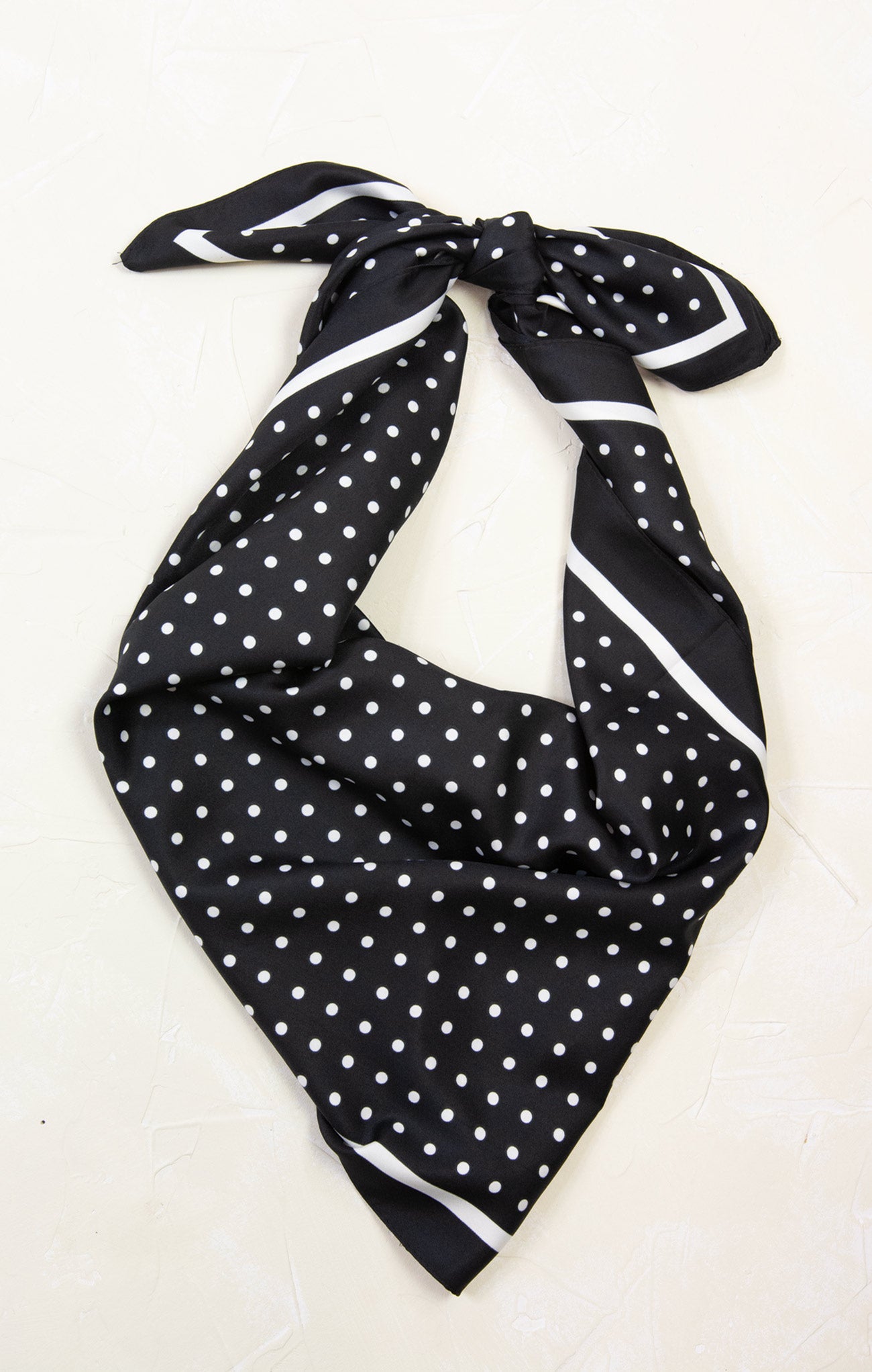 Black polka dot scarf tied on a white background