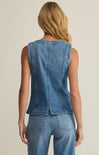 Person wearing a blue denim vest and jeans on a beige background