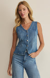 Woman wearing a denim vest and jeans against a beige background