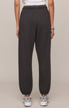 Person wearing dark gray sweatpants on a beige background