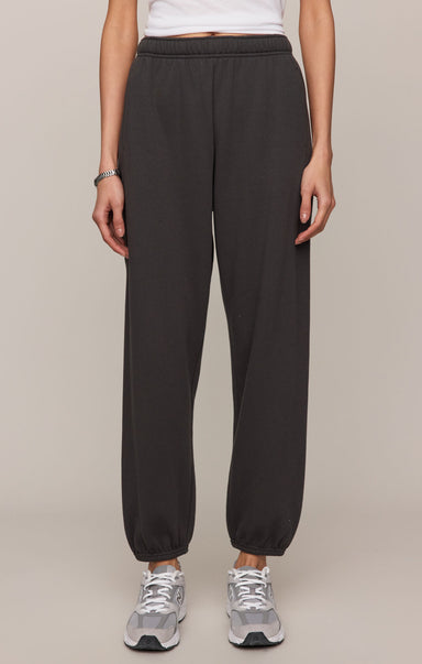 Person wearing black sweatpants on a beige background