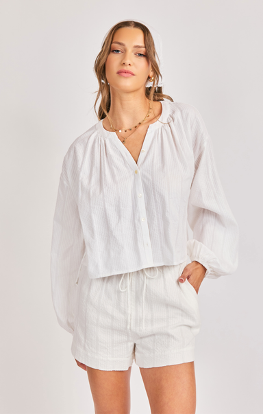 Woman wearing a white blouse and shorts on a plain background