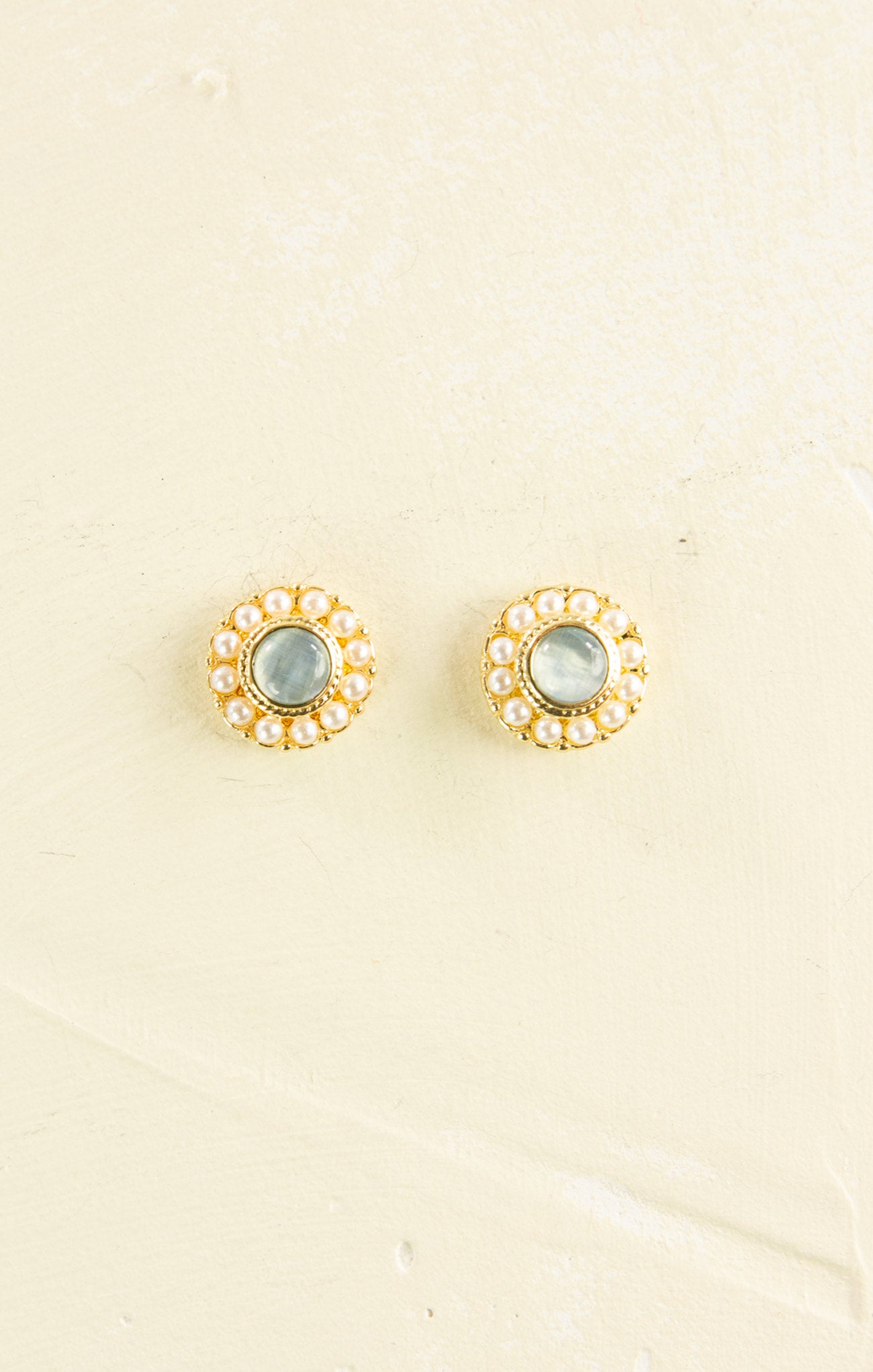 Pair of gold earrings with gemstones on a beige background