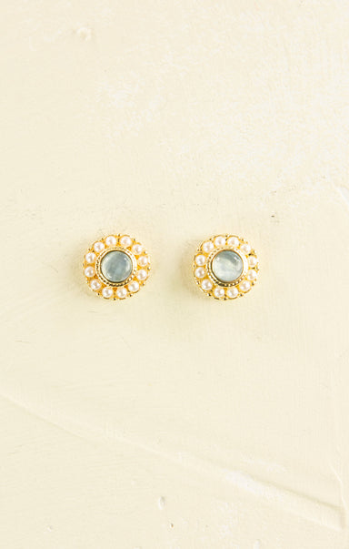 Pair of gold earrings with gemstones on a beige background