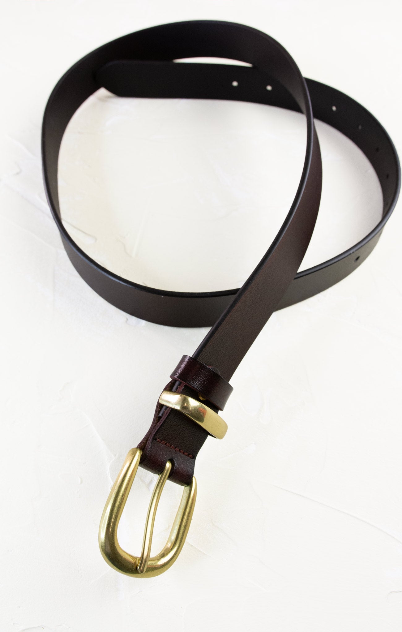 Brown leather belt with a gold buckle on a white background