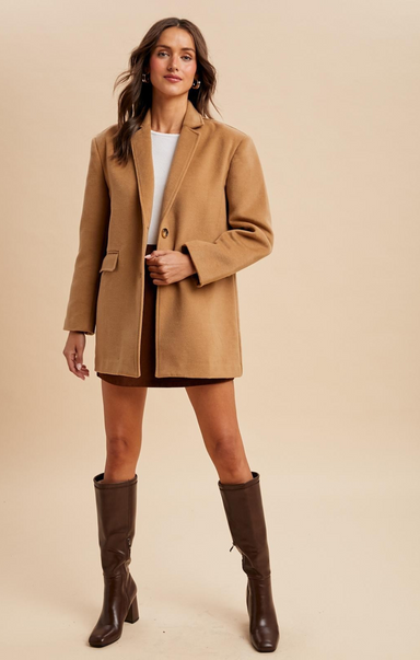 Woman wearing a tan coat and brown knee-high boots on a beige background