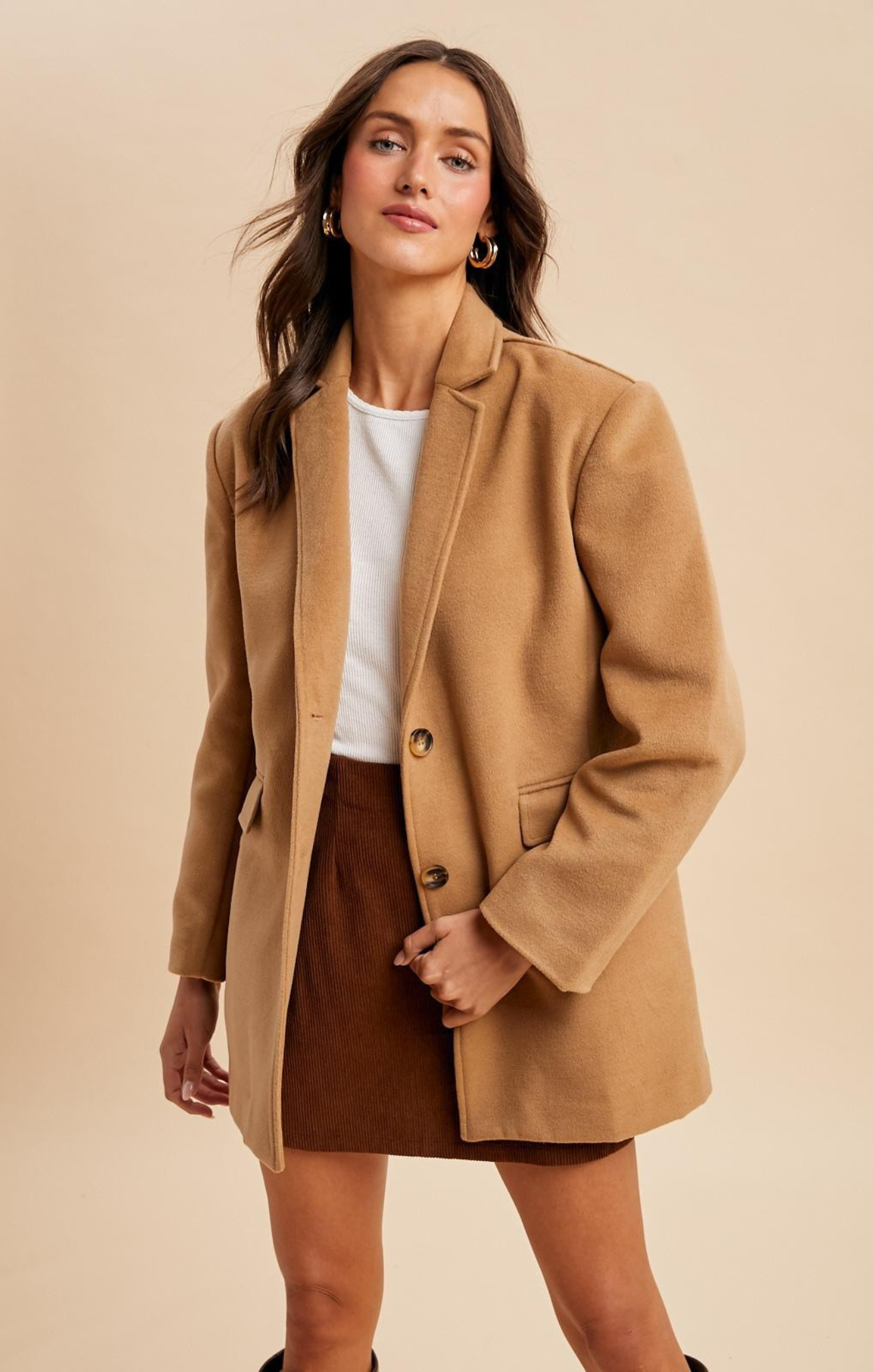 Woman wearing a brown coat and skirt on a beige background