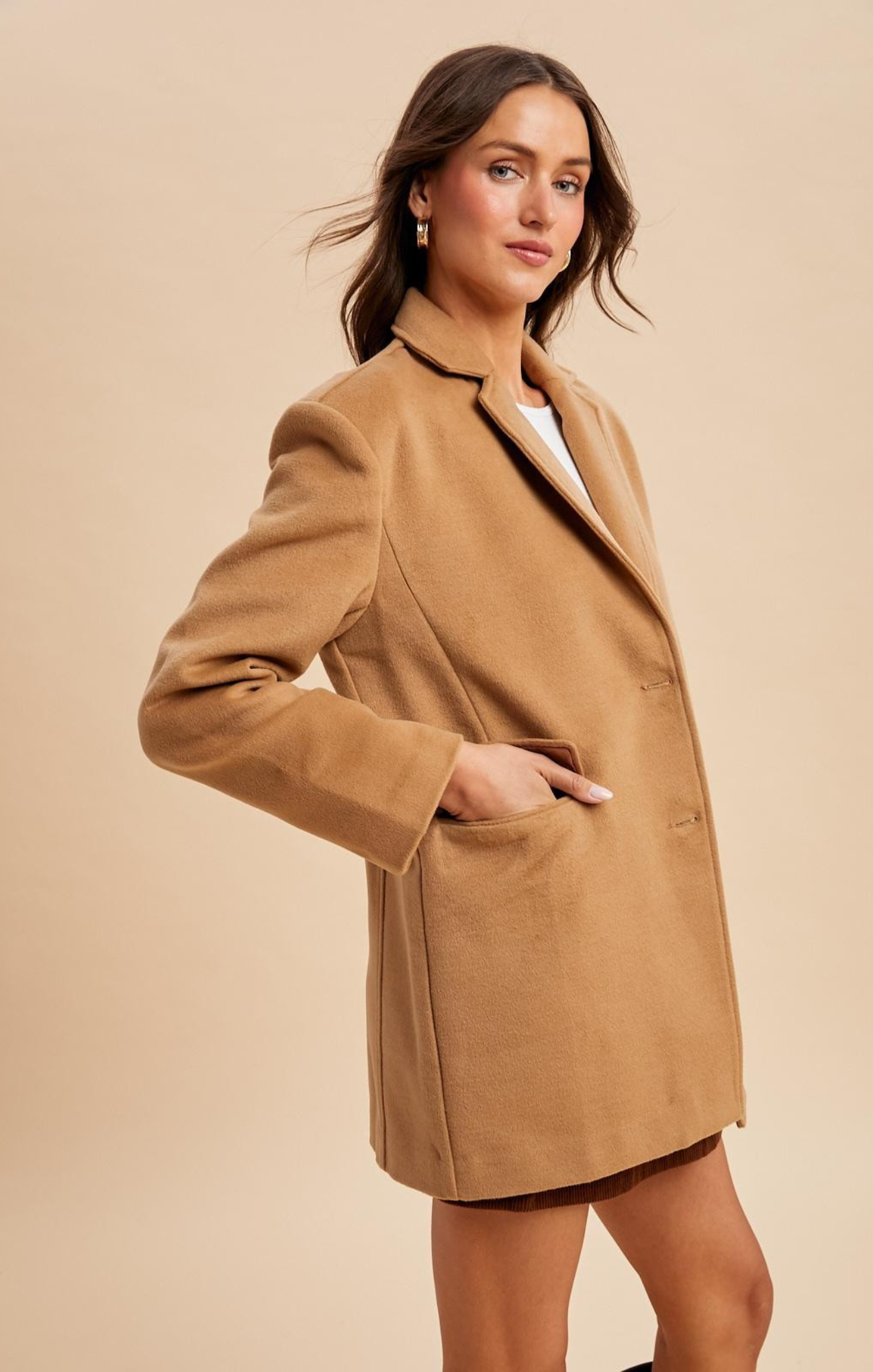 Woman wearing a tan coat against a beige background