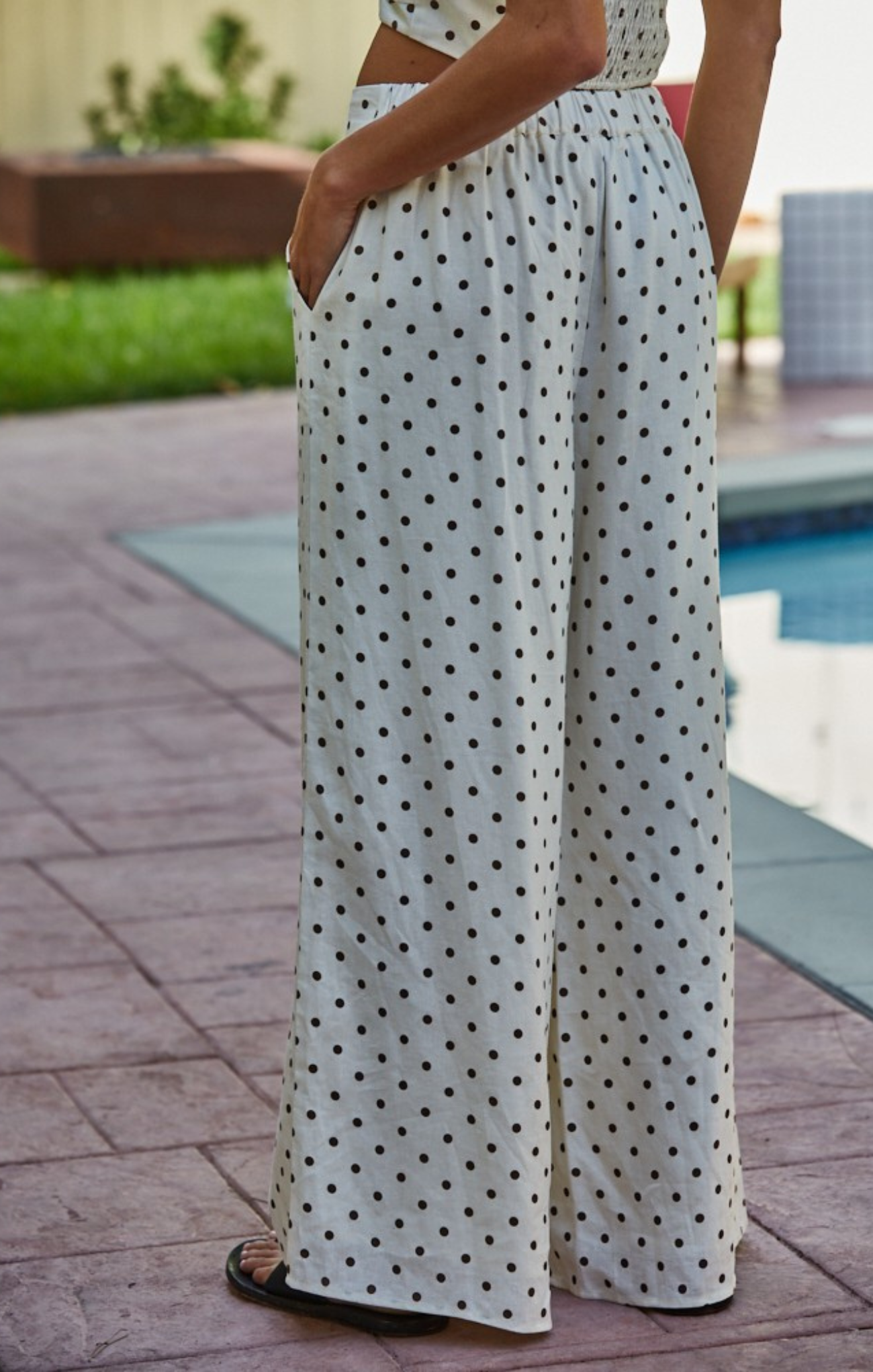 Person wearing a polka dot dress by a poolside