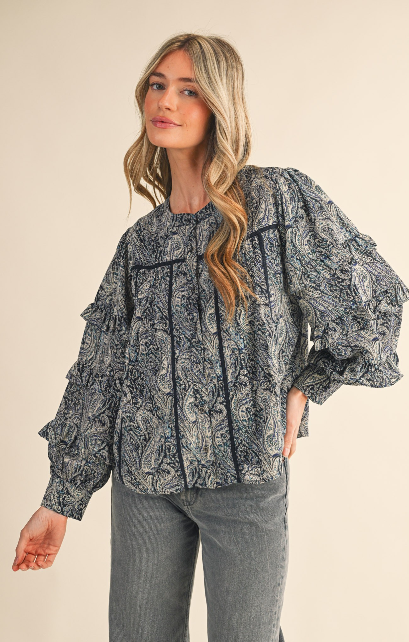 Woman wearing a patterned blouse with long sleeves on a beige background