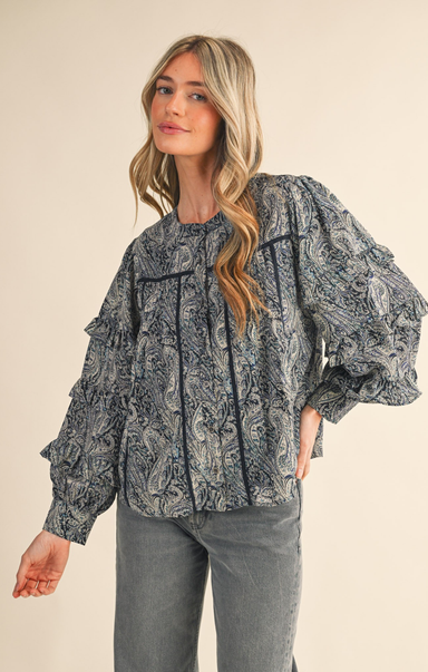 Woman wearing a patterned blouse with long sleeves on a beige background