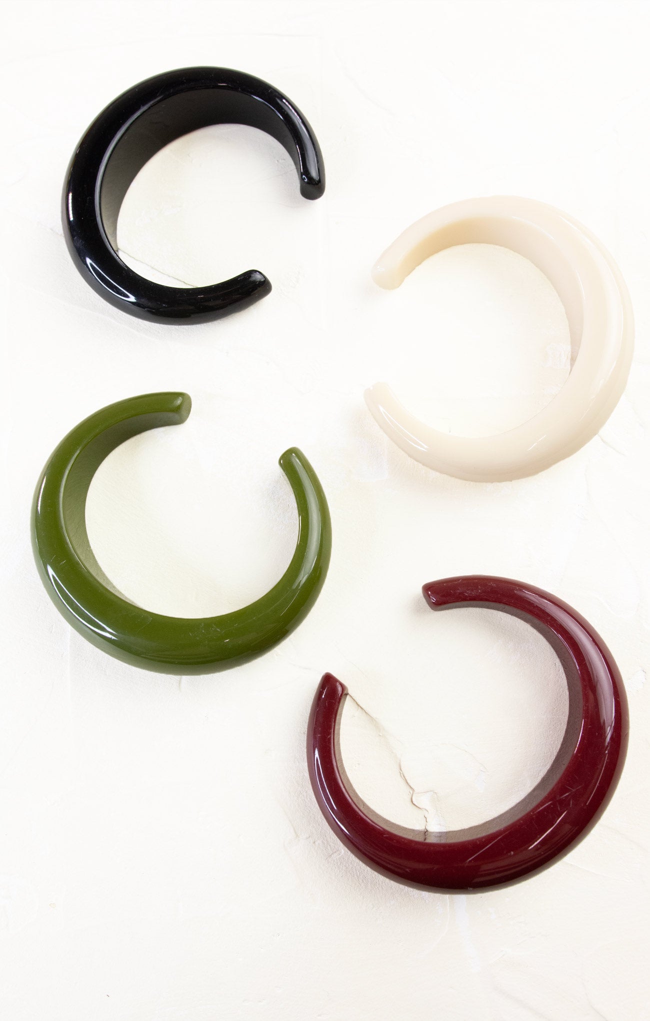 Four ear gauges in black, white, green, and red on a white background