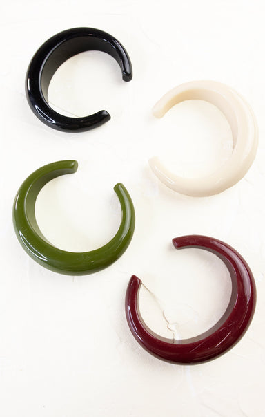 Four ear gauges in black, white, green, and red on a white background