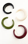 Four ear gauges in black, white, green, and red on a white background