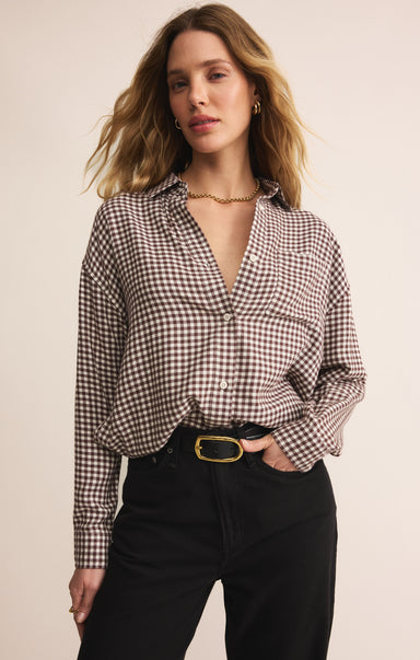 Woman wearing a checkered shirt and black pants against a beige background