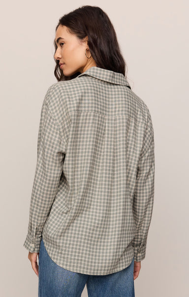 Woman wearing a plaid shirt and jeans against a plain background