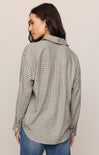 Woman wearing a plaid shirt and jeans against a plain background