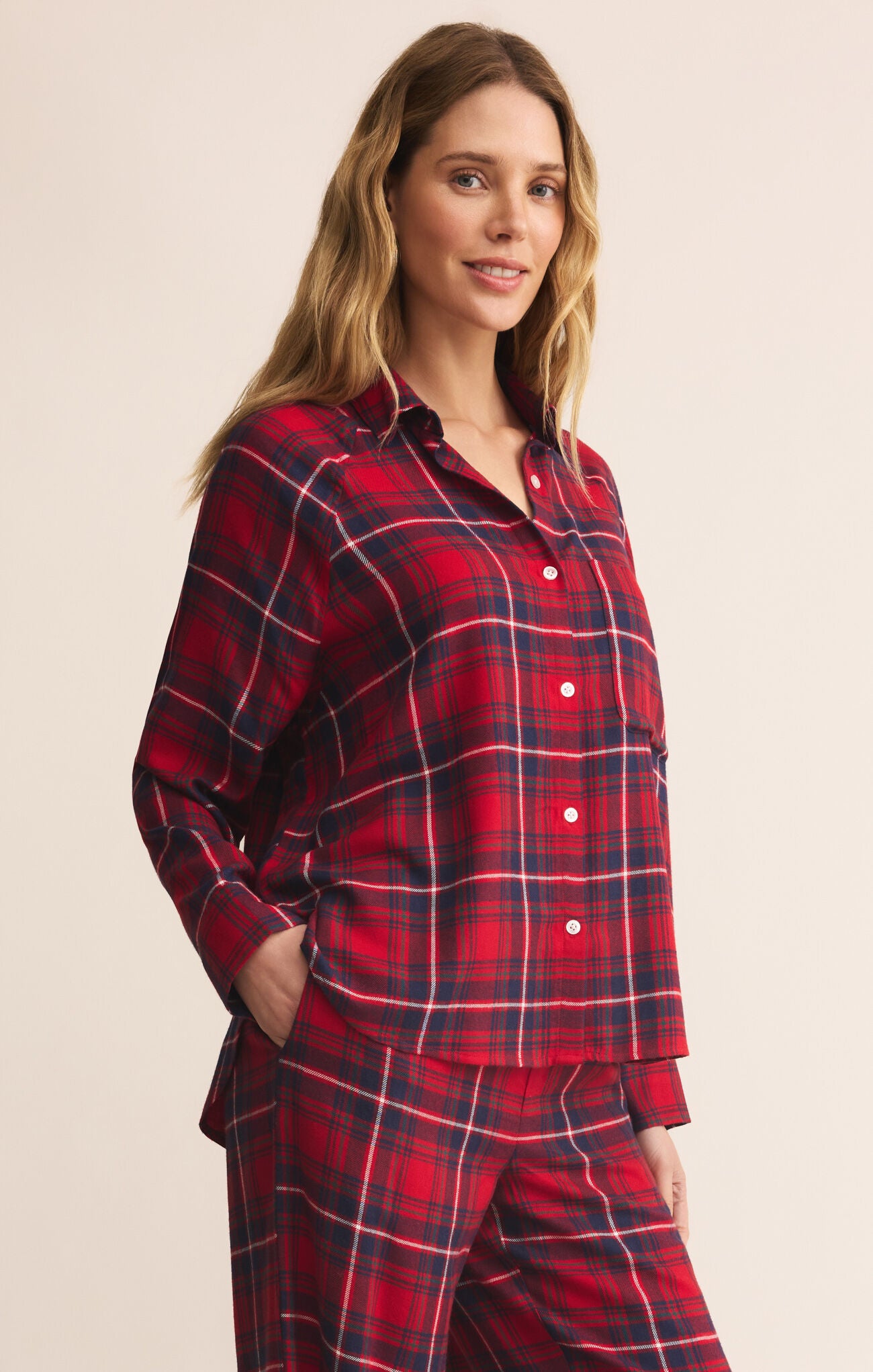 Woman wearing red plaid pajamas against a beige background