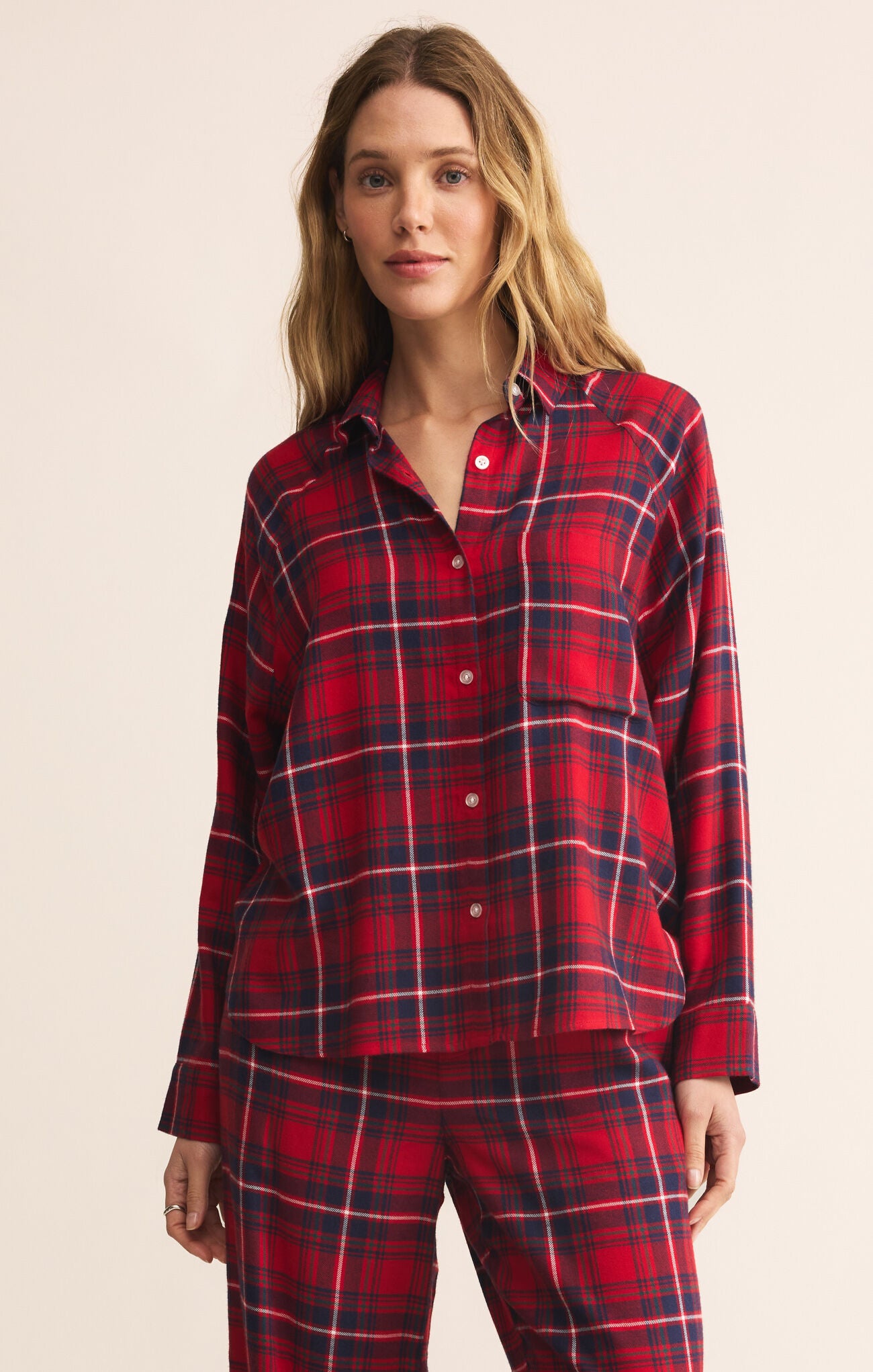 Woman wearing a red plaid pajama set against a beige background